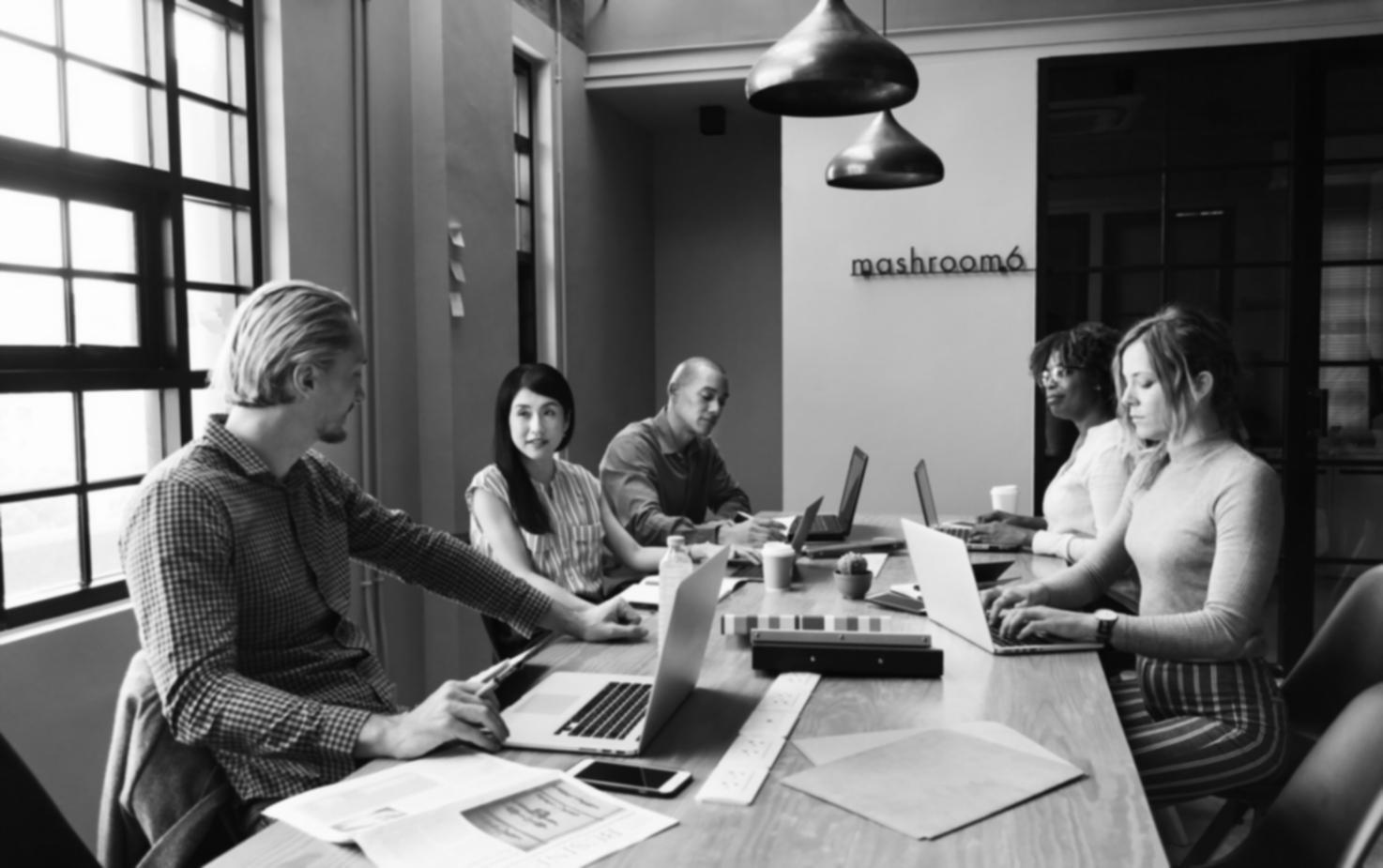Team collaboration session with financial charts and performance metrics displayed on monitors in a modern workspace